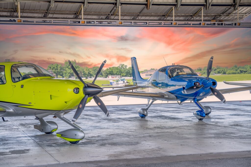 Yellow and blue Cirrus aircraft in the hangar at sunset, Bowman Field Louisville