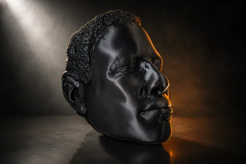 Life-size 3D printed head prototype in black filament, showing print layer detail