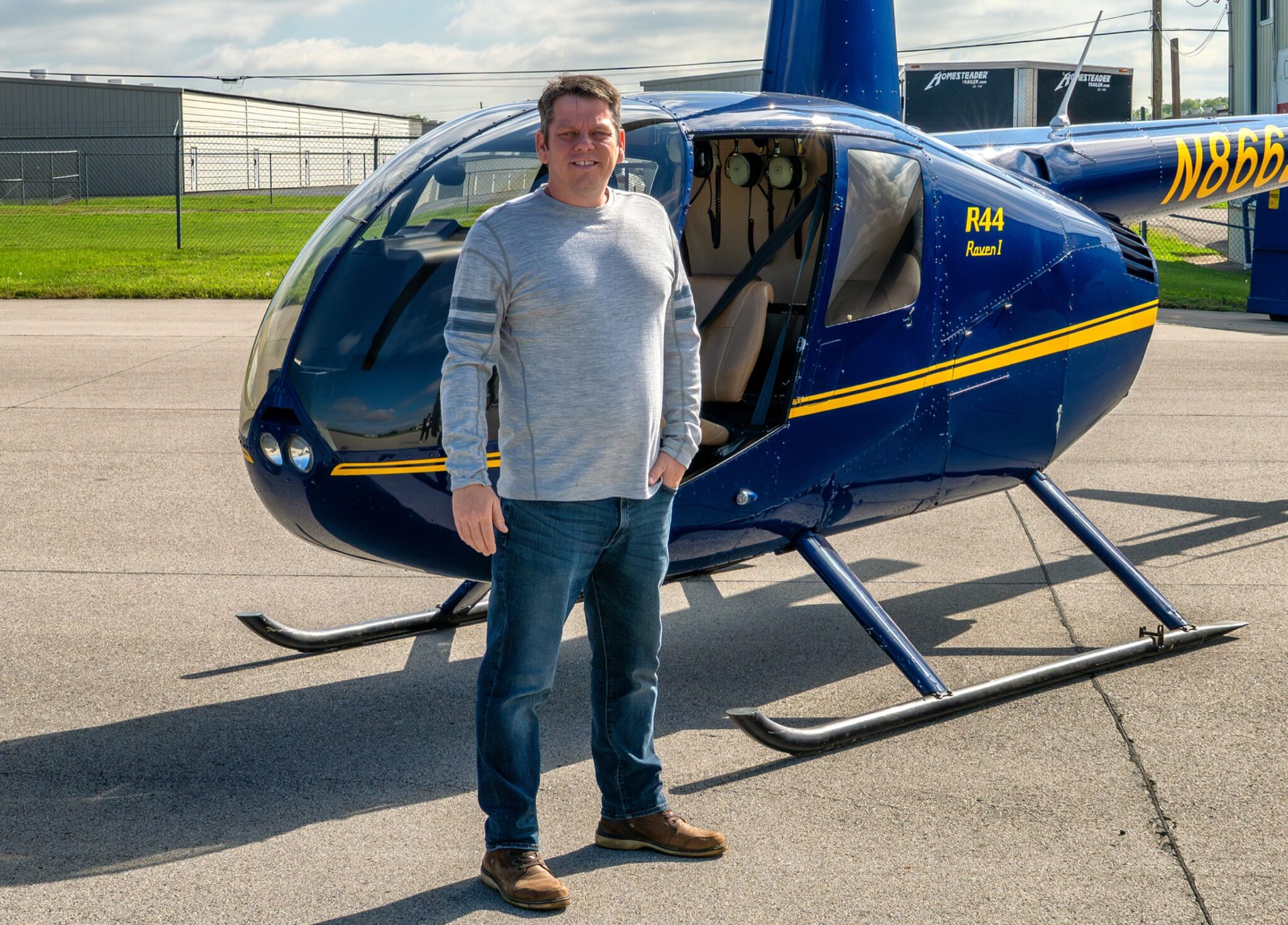Shaun Wilson standing in front of a Robinson R44 helicopter before an aerial photography flight