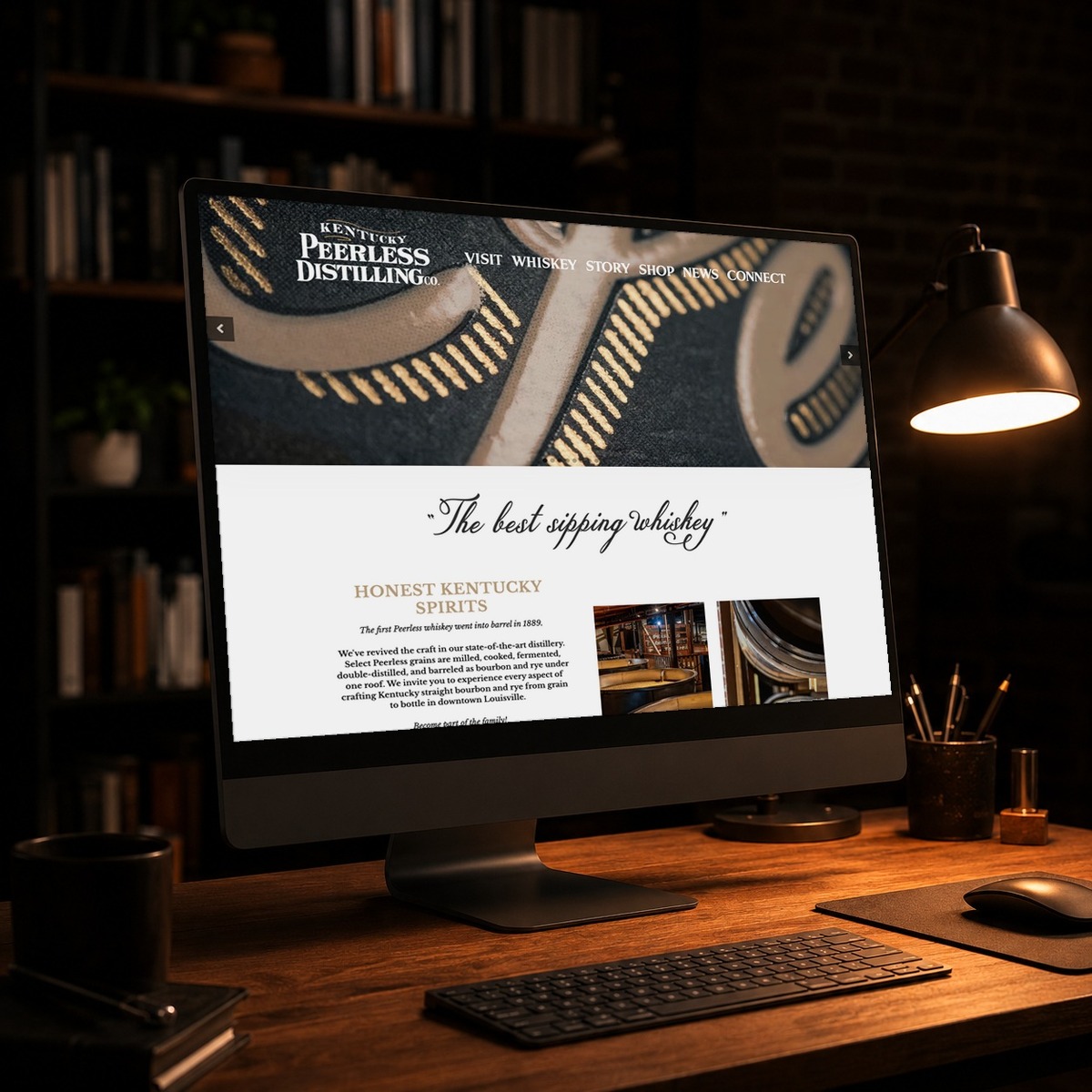 Kentucky Peerless Distilling website on a desktop monitor in a dark studio, web design by Shaun Wilson Designs in Louisville